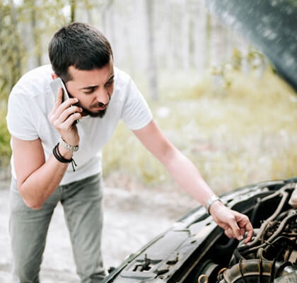 Man looking into hood of car