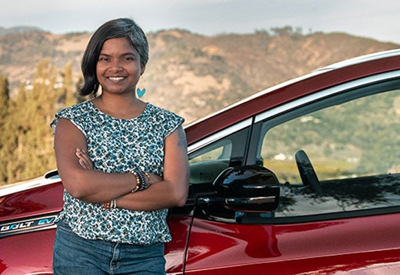 Woman smiling and leaning on a red car