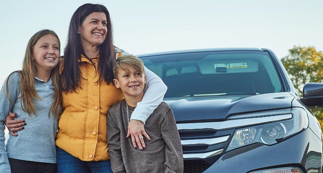 Andrea standing with family and car